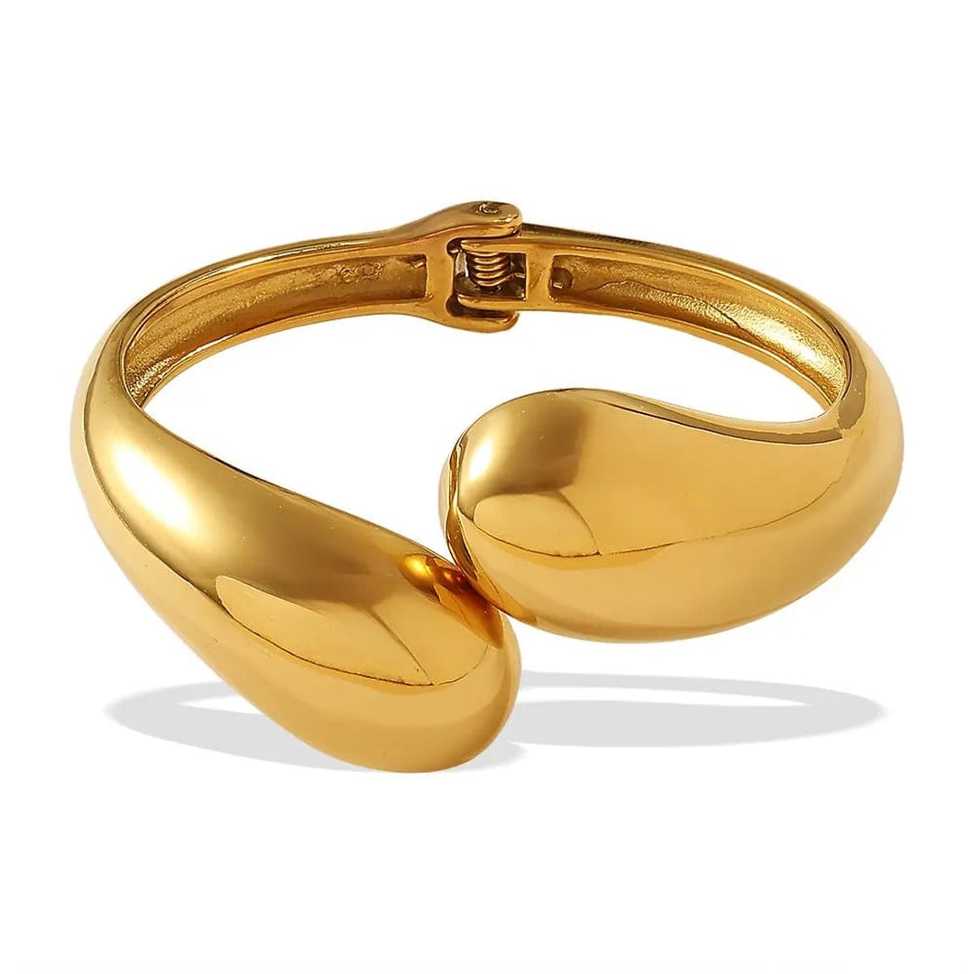 A polished gold-tone metal cuff bracelet with a unique organic, rounded teardrop-like design, shown on a clean white background with a soft shadow.
