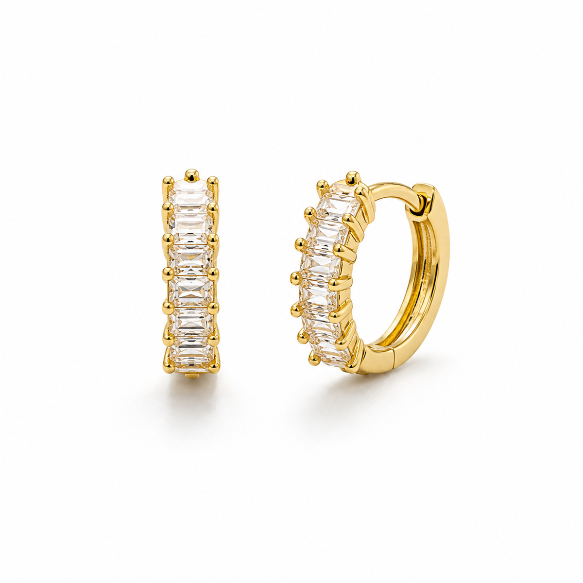 A pair of gold huggie hoop earrings with a row of baguette-cut clear stones, shown on a clean white background.