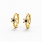 A pair of gold huggie hoop earrings with a star-shaped floral center, featuring a small black round stone surrounded by clear stones, set against a plain white background.